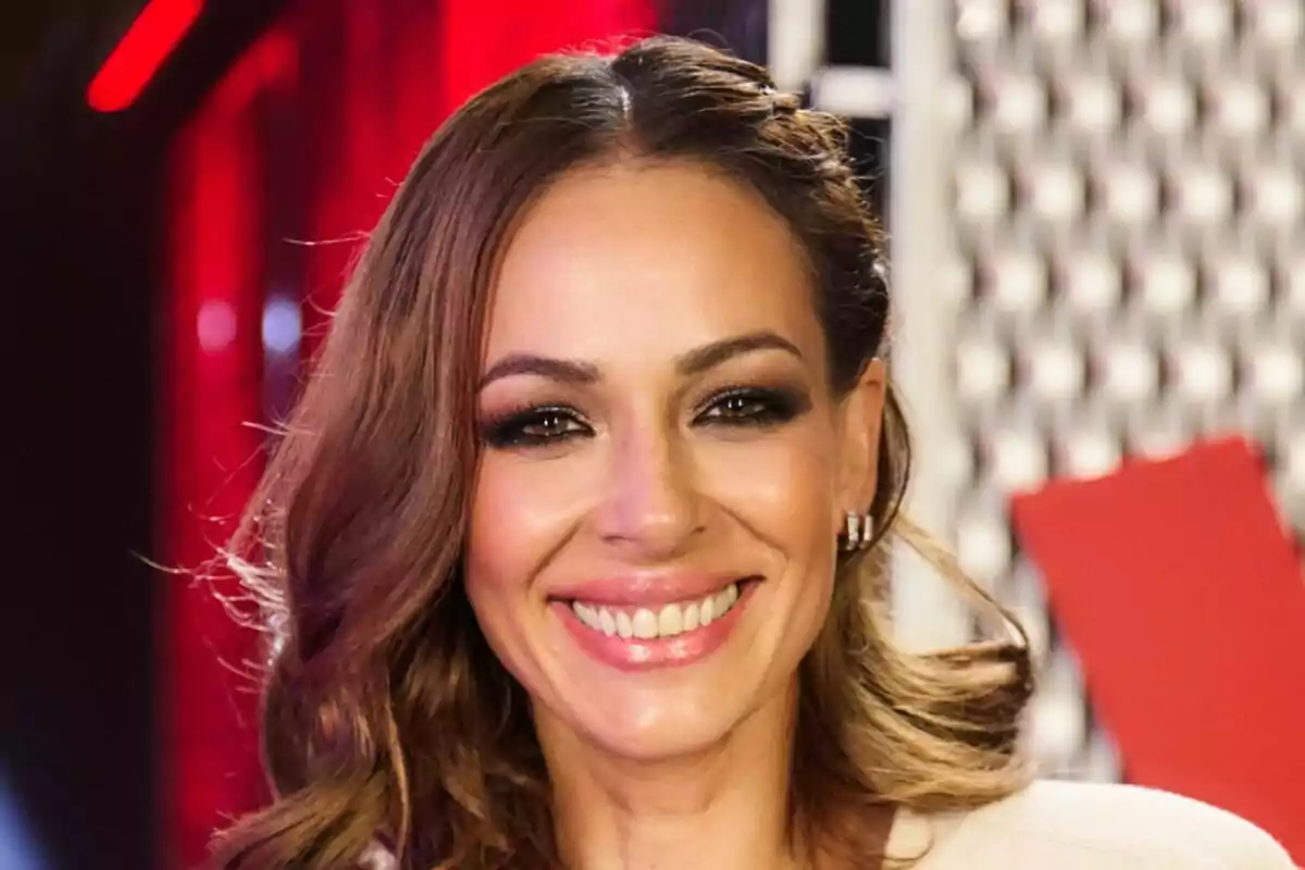 Eva González sonriendo con fondo rojo y negro en La Voz Kids.
