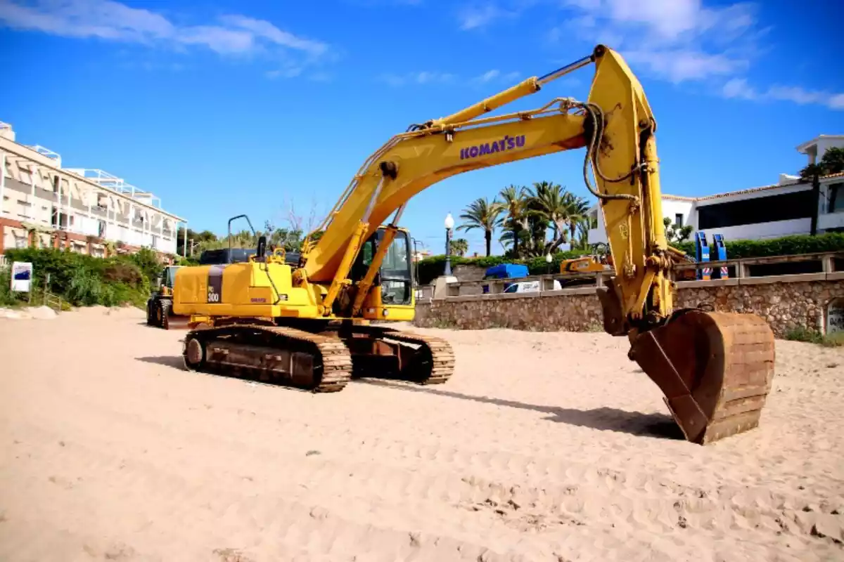Una máquina removiendo tierra de una playa de Barcelona para llevarla a otra Una máquina removiendo tierra de una playa de Barcelona para llevarla a otra
