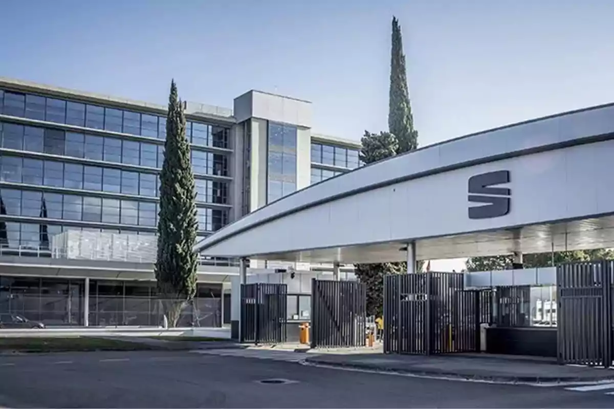 Edificio moderno con fachada de vidrio y entrada con estructura metálica y logotipo en la parte superior. Edificio moderno con fachada de vidrio y entrada con estructura metálica y logotipo en la parte superior.