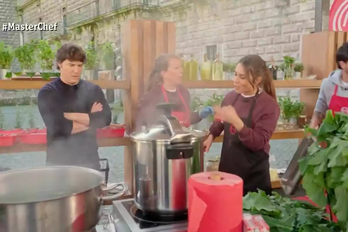 Personas cocinando al aire libre en una competencia de cocina con ollas humeantes y vegetales frescos sobre la mesa en 'Masterchef' Personas cocinando al aire libre en una competencia de cocina con ollas humeantes y vegetales frescos sobre la mesa en 'Masterchef'