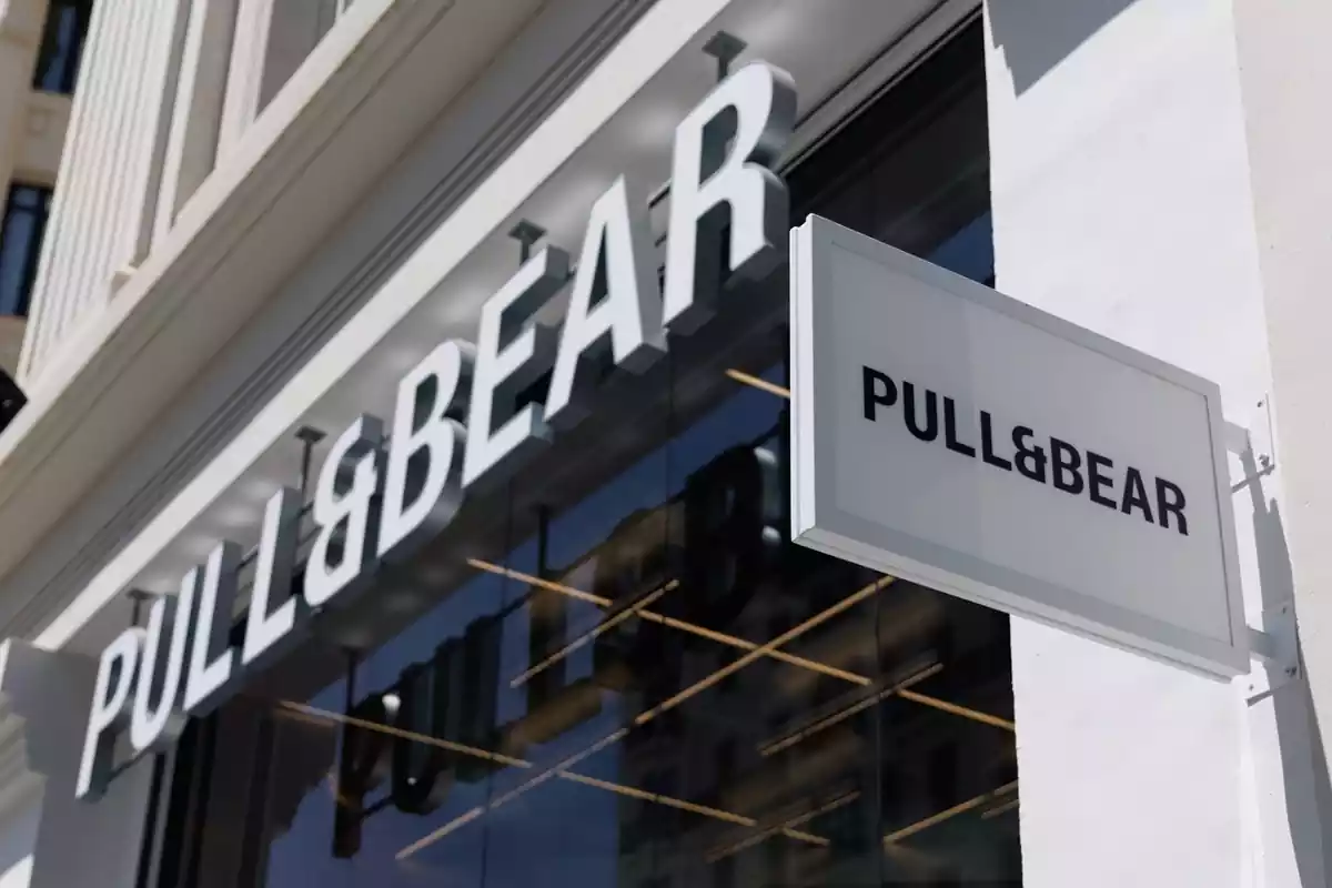 Exterior de una tienda de Pull&Bear con un letrero de grandes dimensiones y un cartel con el logo de la misma marca