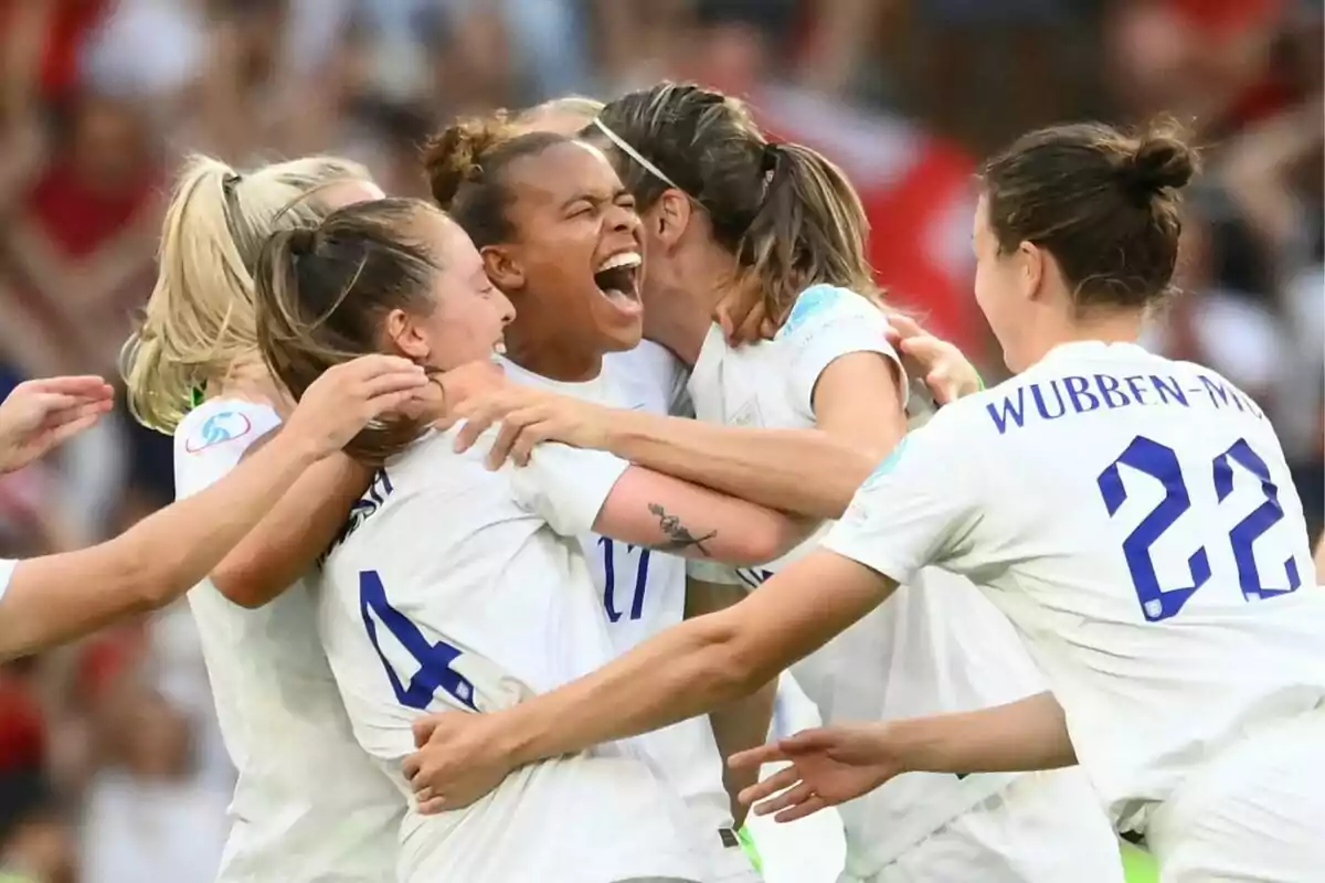 Un grupo de jugadoras de fútbol celebra efusivamente en el campo.
