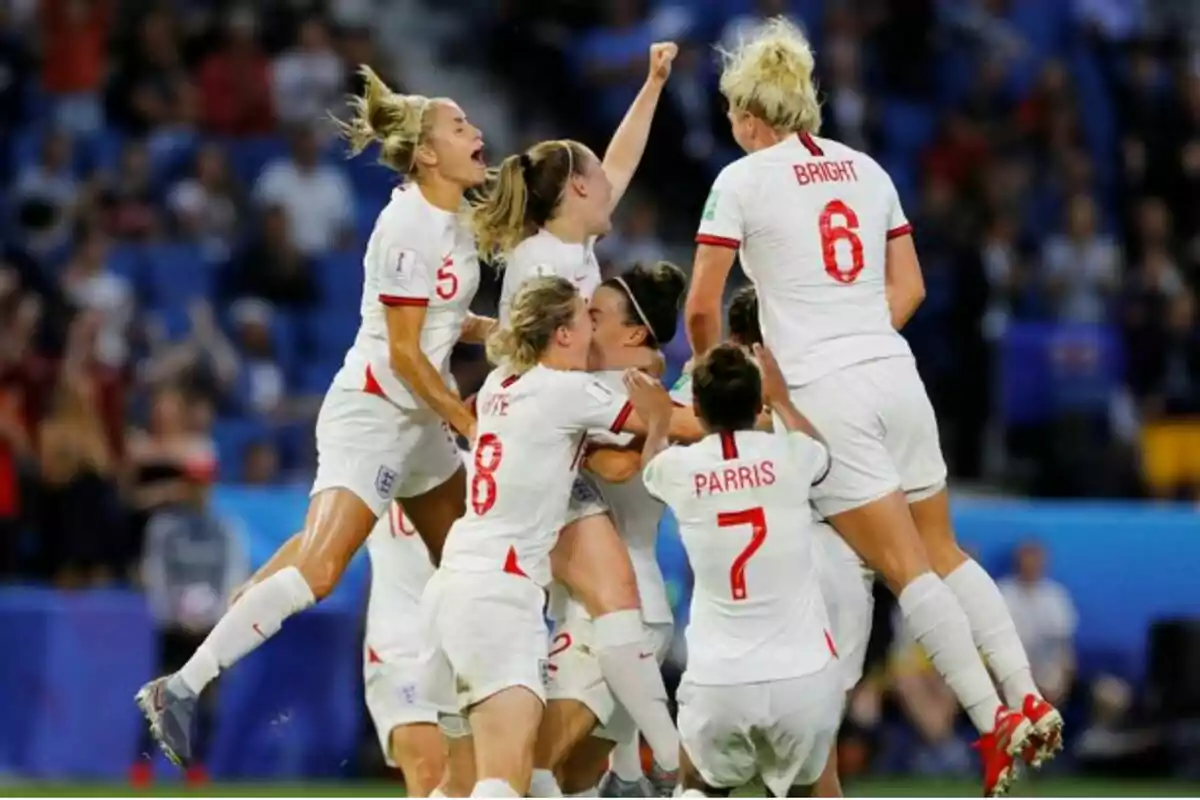 Jugadoras de fútbol celebrando un gol en equipo durante un partido, vistiendo uniformes blancos con detalles rojos. Jugadoras de fútbol celebrando un gol en equipo durante un partido, vistiendo uniformes blancos con detalles rojos.