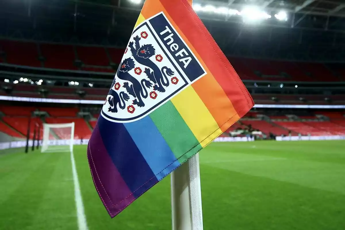 Bandera de esquina con diseño de arcoíris y el logo de The FA en un estadio de fútbol vacío. Bandera de esquina con diseño de arcoíris y el logo de The FA en un estadio de fútbol vacío.