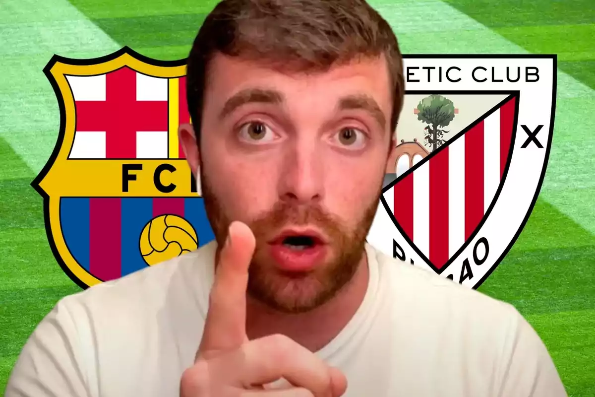 Un hombre con barba y camiseta blanca señala con el dedo índice hacia la cámara, con los escudos del FC Barcelona y el Athletic Club de Bilbao de fondo sobre un campo de fútbol.