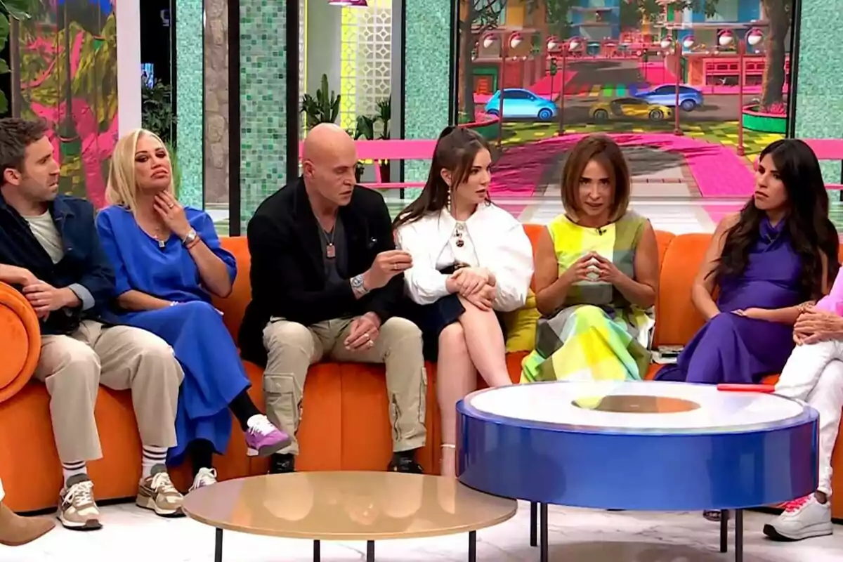 Un grupo de personas formado por Aitor Albizua, Belén Esteban, Kiko Matamoros, Inés Hernand, María Patiño e Isa Pantoja está sentado en un sofá color naranja en un set de televisión de La Familia de la Tele, conversando y prestando atención a la discusión.