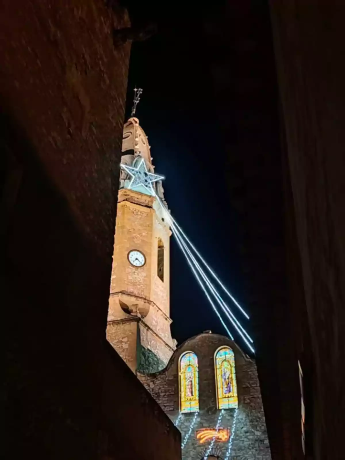Torre de iglesia iluminada con una estrella y luces navideñas en la noche. Torre de iglesia iluminada con una estrella y luces navideñas en la noche.