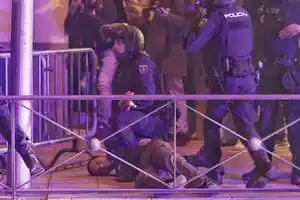 Un policía antidisturbios con la cara pixelada retiene un manifestante delante de la sede del PSOE en la calle Ferraz de Madrid