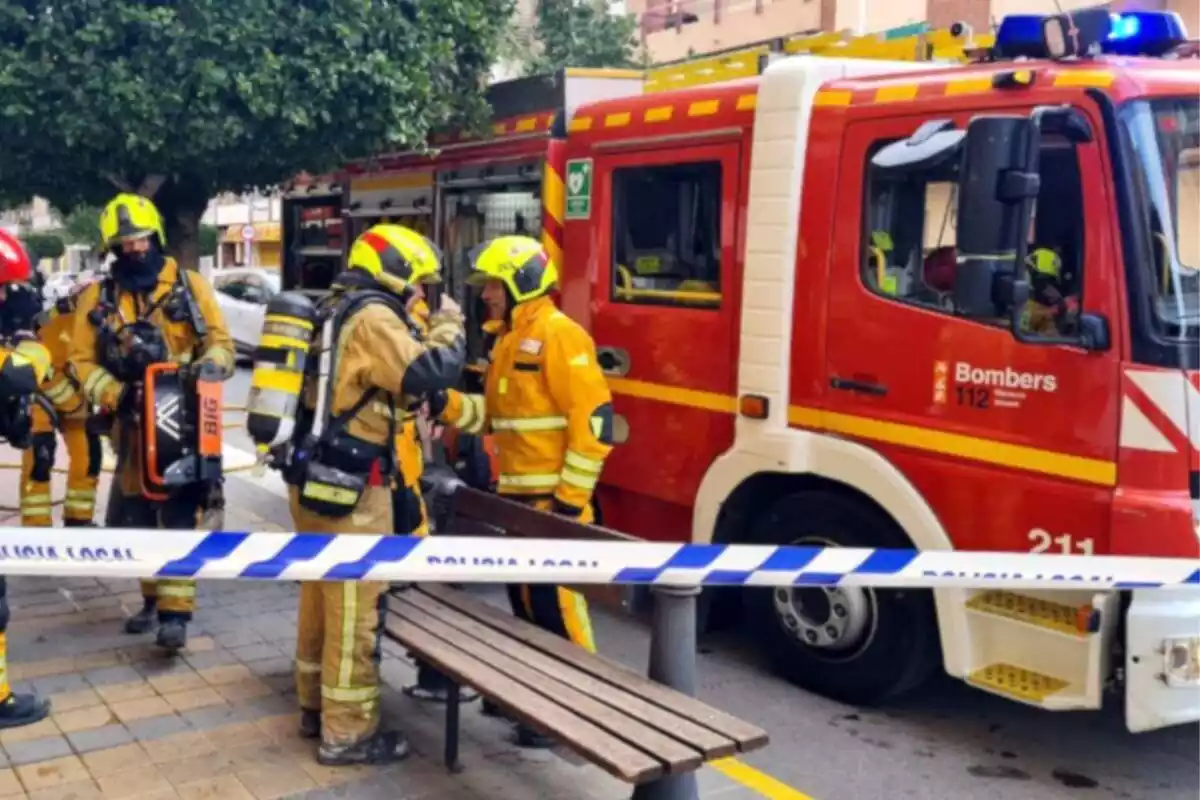Foto de una dotación de los bomberos de Alicante y varios bomberos y una cinta de la Policía Local