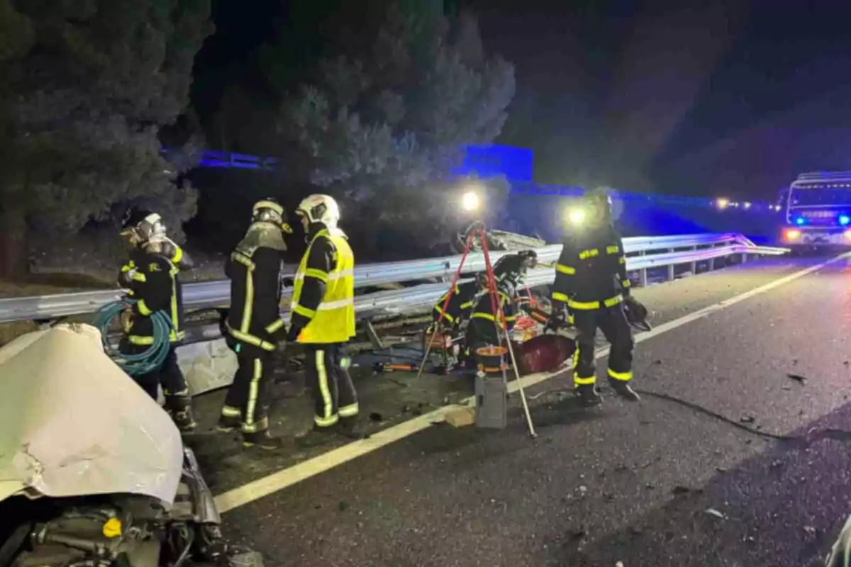 Bomberos trabajando en la escena de un accidente de tráfico en una carretera por la noche.