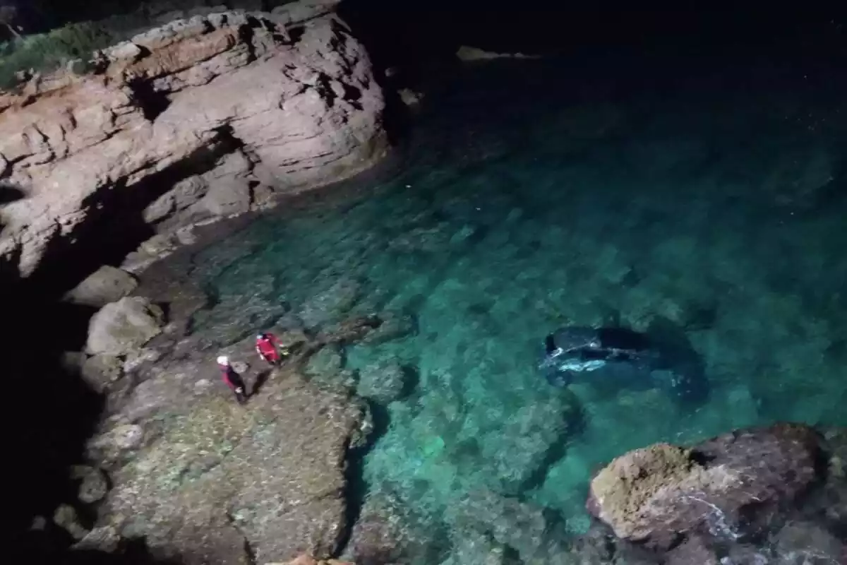 Foto del coche accidentado en Ametlla de Mar y los Bombers rescatando