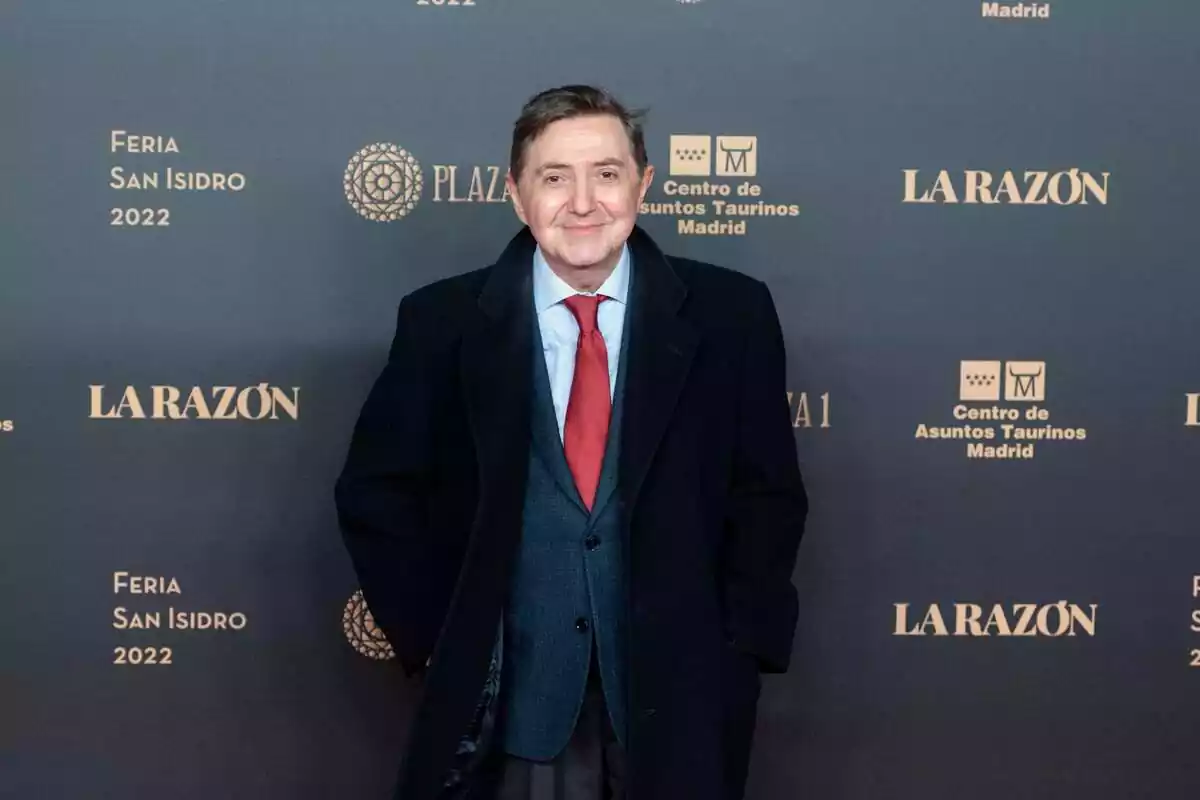 Foto de Federico Jiménez Losantos posando en un photocall sonriente y vestido de gala con una gabardina, un traje azul y una corbata roja Foto de Federico Jiménez Losantos posando en un photocall sonriente y vestido de gala con una gabardina, un traje azul y una corbata roja