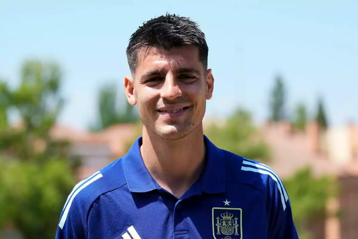 Hombre con camiseta azul de la selección española de fútbol sonriendo al aire libre.