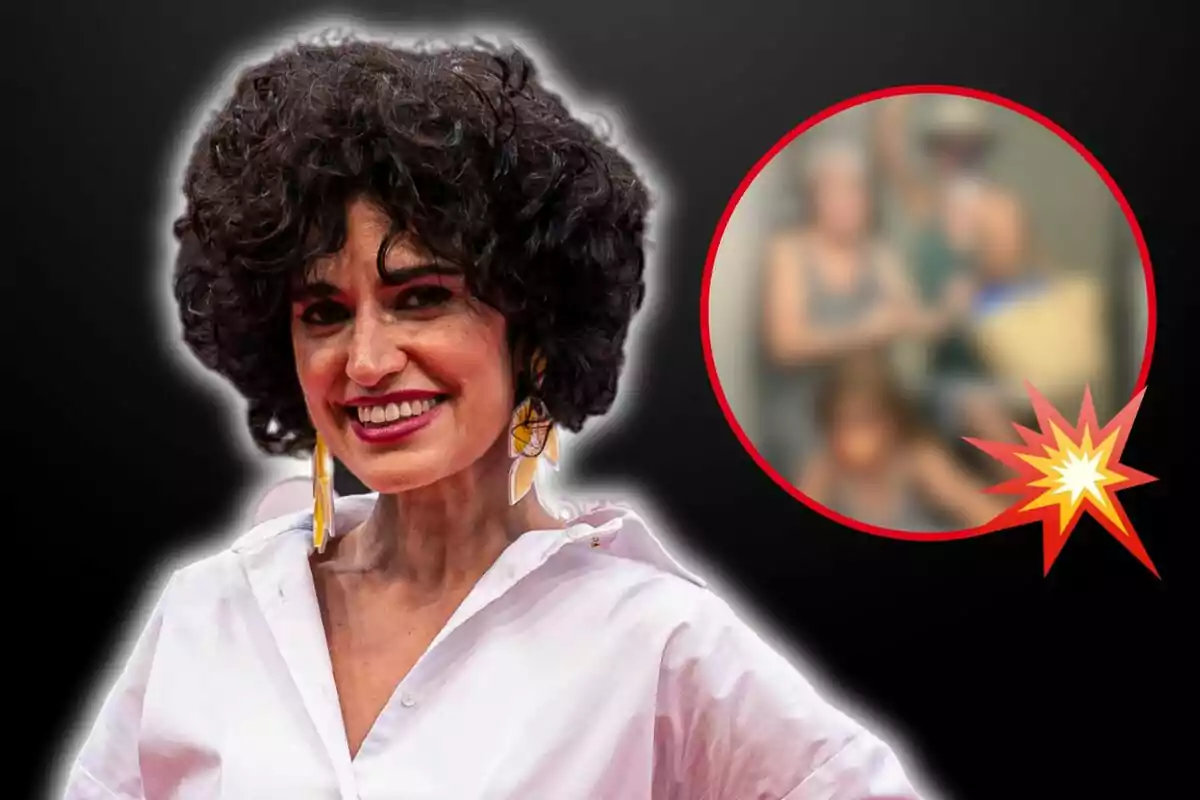 Una mujer sonriente con cabello rizado y aretes grandes, vestida con una camisa blanca, aparece en primer plano sobre un fondo negro; en la esquina superior derecha hay un círculo rojo con una imagen borrosa de varias personas.