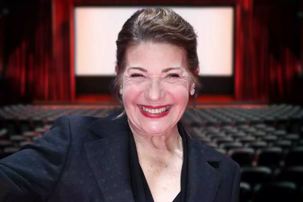 Una mujer sonriente en un cine vacío con una pantalla grande al fondo.