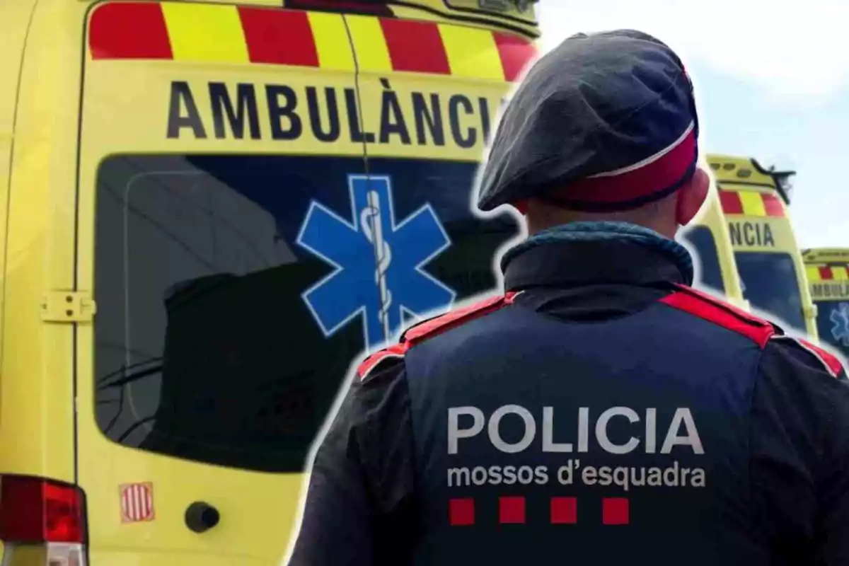 Un agente de la policía de los Mossos d'Esquadra de espaldas frente a una ambulancia amarilla con la palabra "AMBULÀNCIA" escrita en la parte trasera.