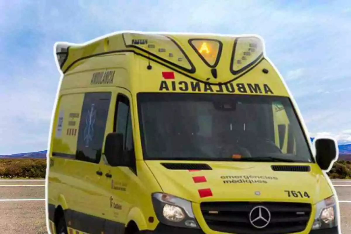 Una ambulancia amarilla con la palabra "AMBULANCIA" escrita en la parte frontal y lateral, estacionada en una carretera con un cielo azul de fondo.