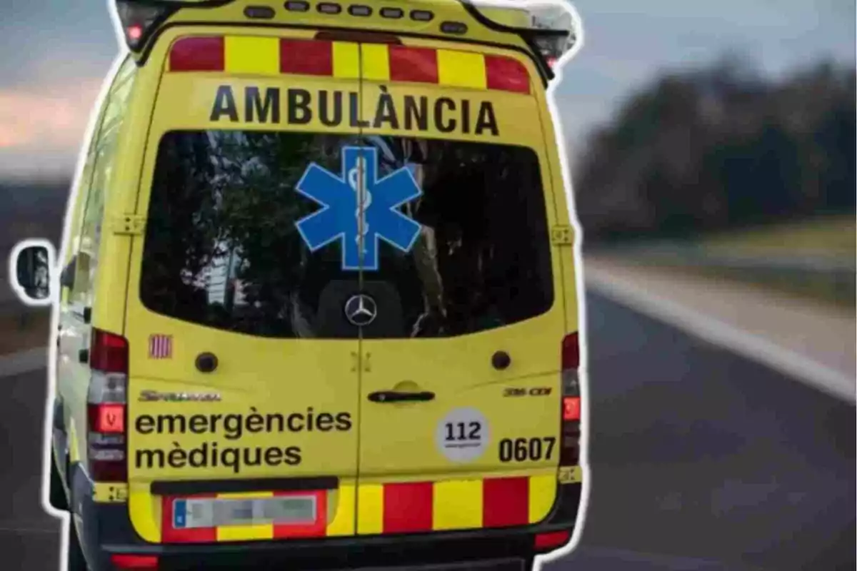 Una ambulancia amarilla con la palabra "AMBULÀNCIA" en la parte superior trasera y "emergències mèdiques" en la parte inferior, con una estrella azul de la vida en el centro y el número de emergencia 112.