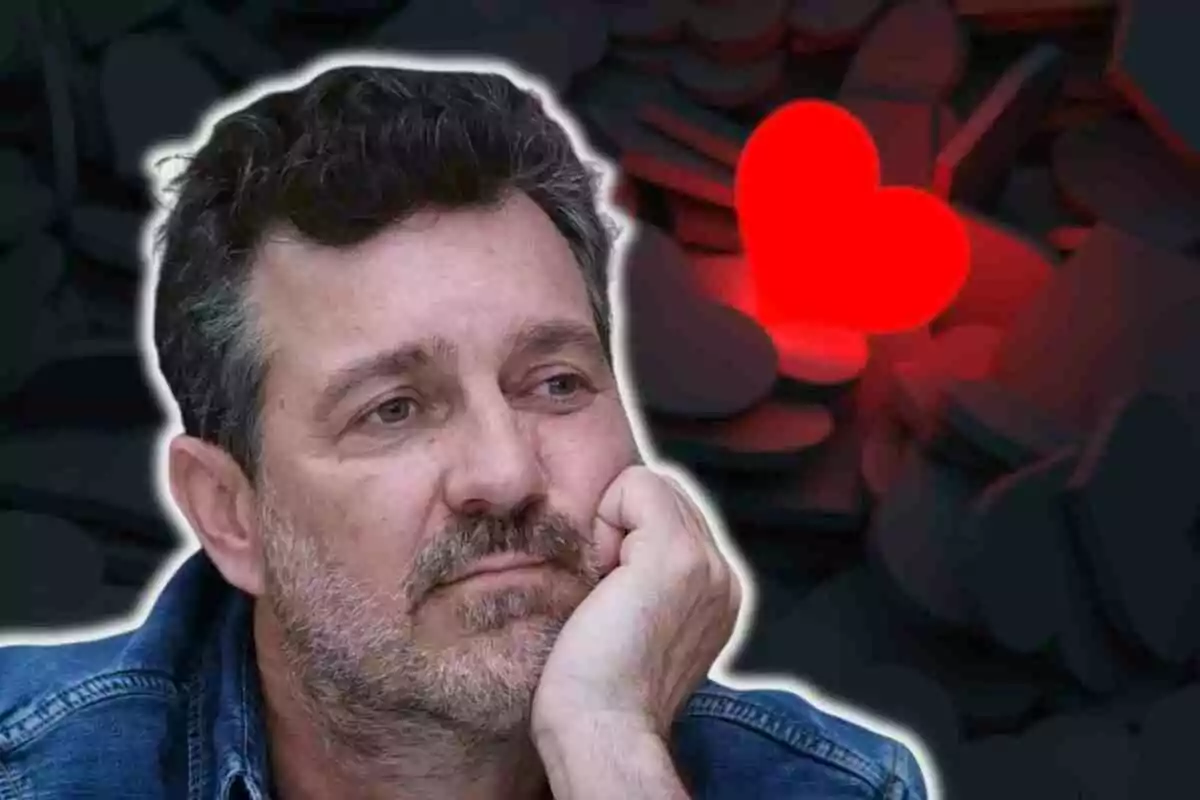 Marc Cartes con barba y cabello oscuro, apoyando su cabeza en su mano, con un fondo de corazones oscuros y un corazón rojo brillante.