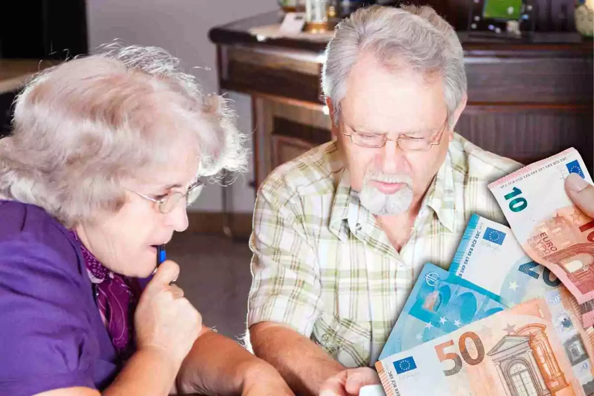 Dos personas mayores revisando billetes de euro en una mesa.