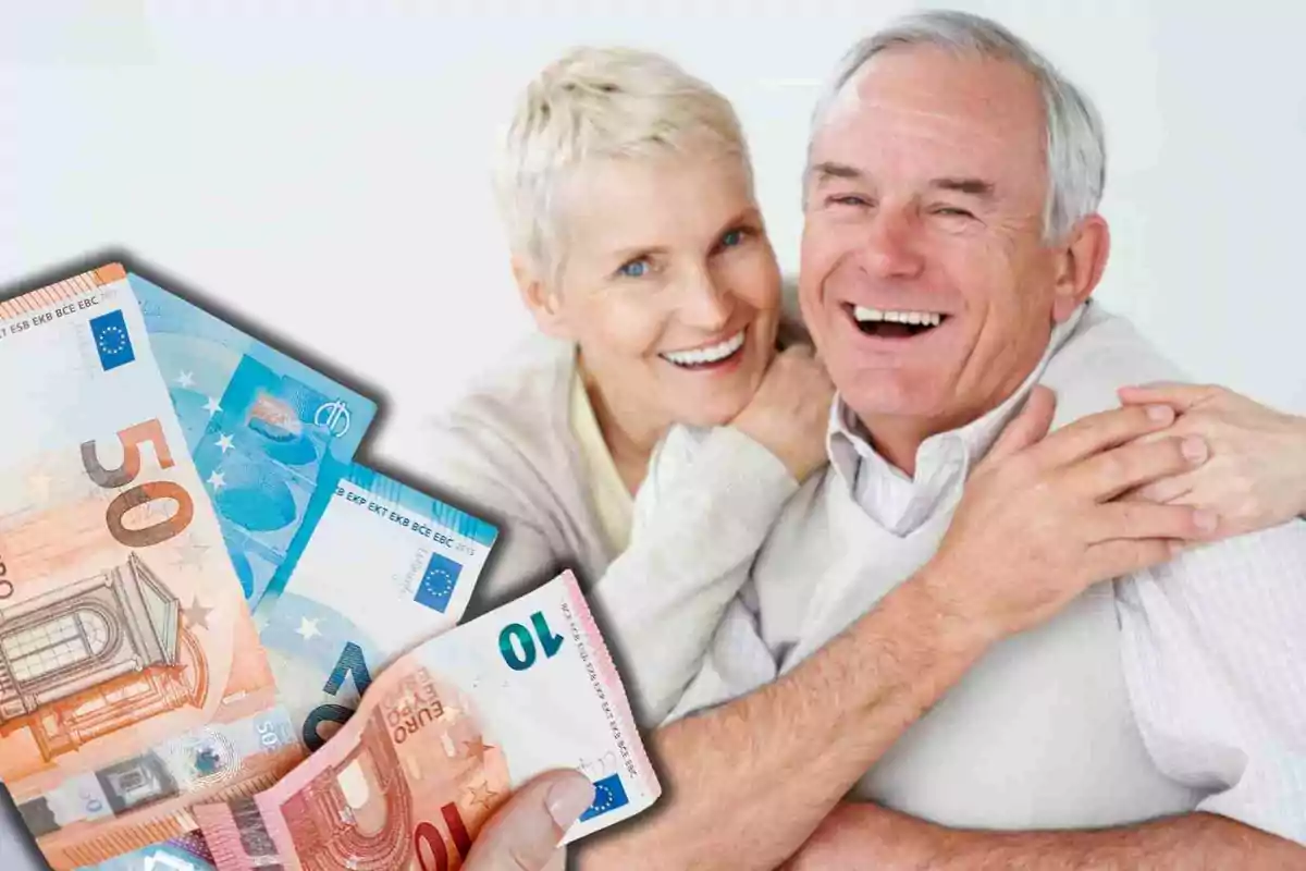 Pareja de personas mayores sonriendo con billetes de euros en primer plano.