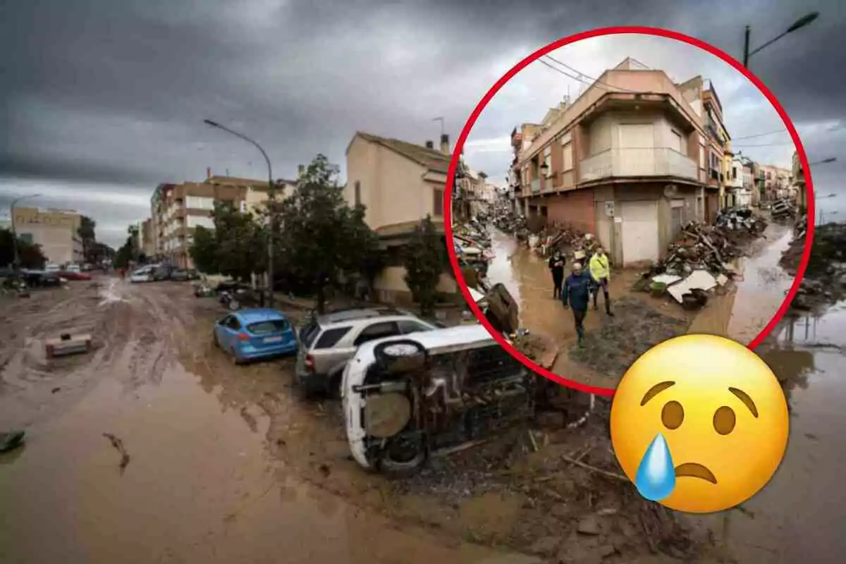 Calle inundada con coches volcados y escombros tras una tormenta en Paiporta, con un emoji triste superpuesto.