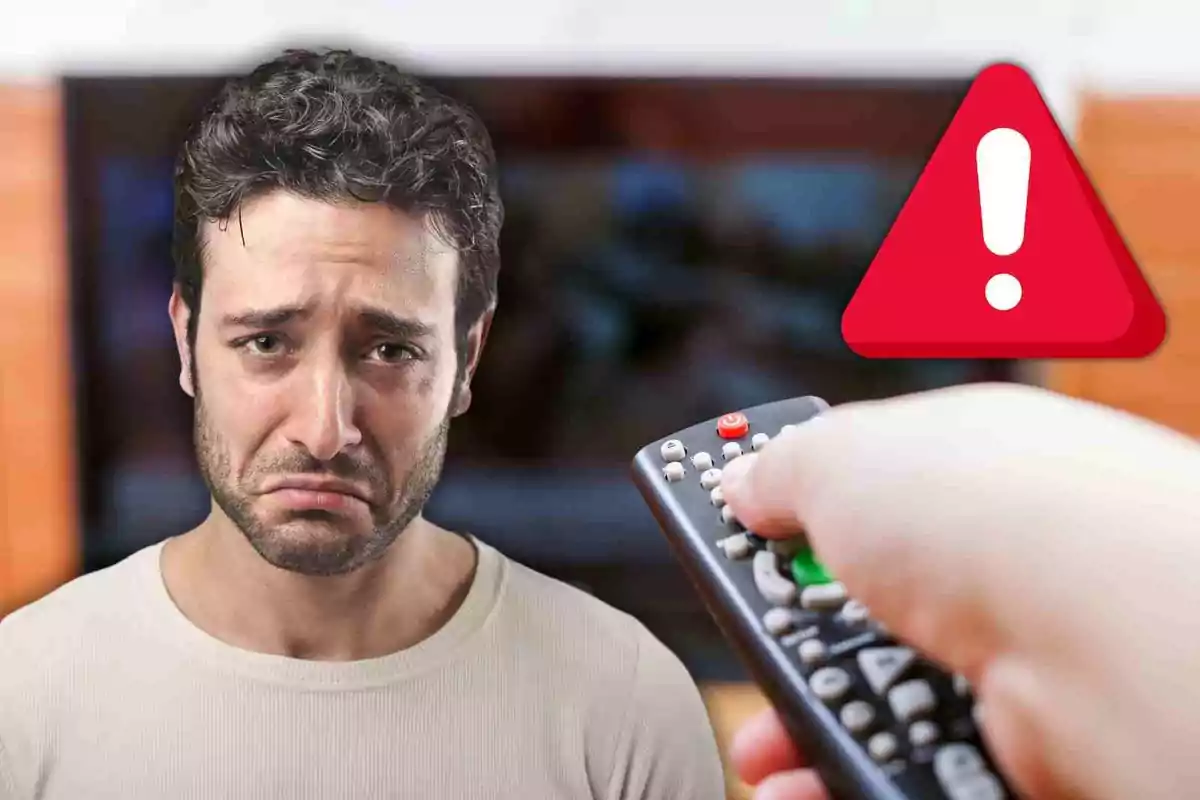 Hombre con expresión triste mientras alguien sostiene un control remoto frente a un televisor con un ícono de advertencia.