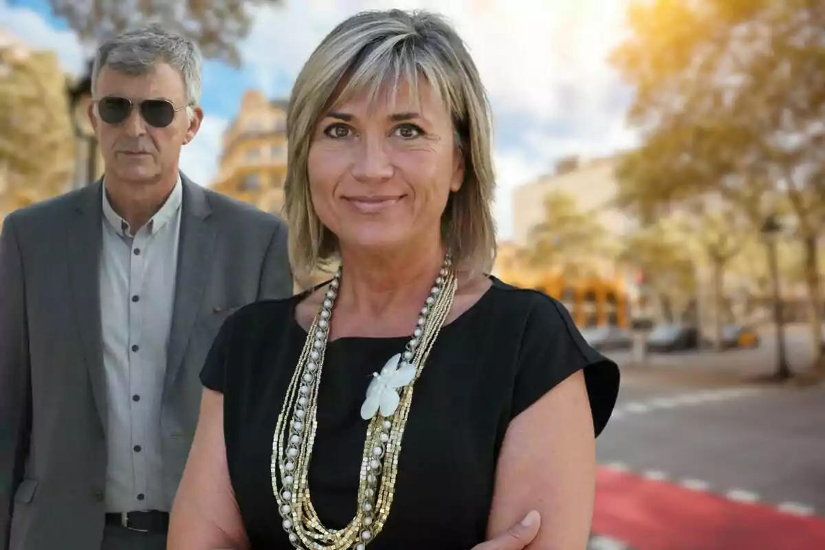 Una mujer sonriente con un collar llamativo y un hombre con gafas de sol en un entorno urbano.