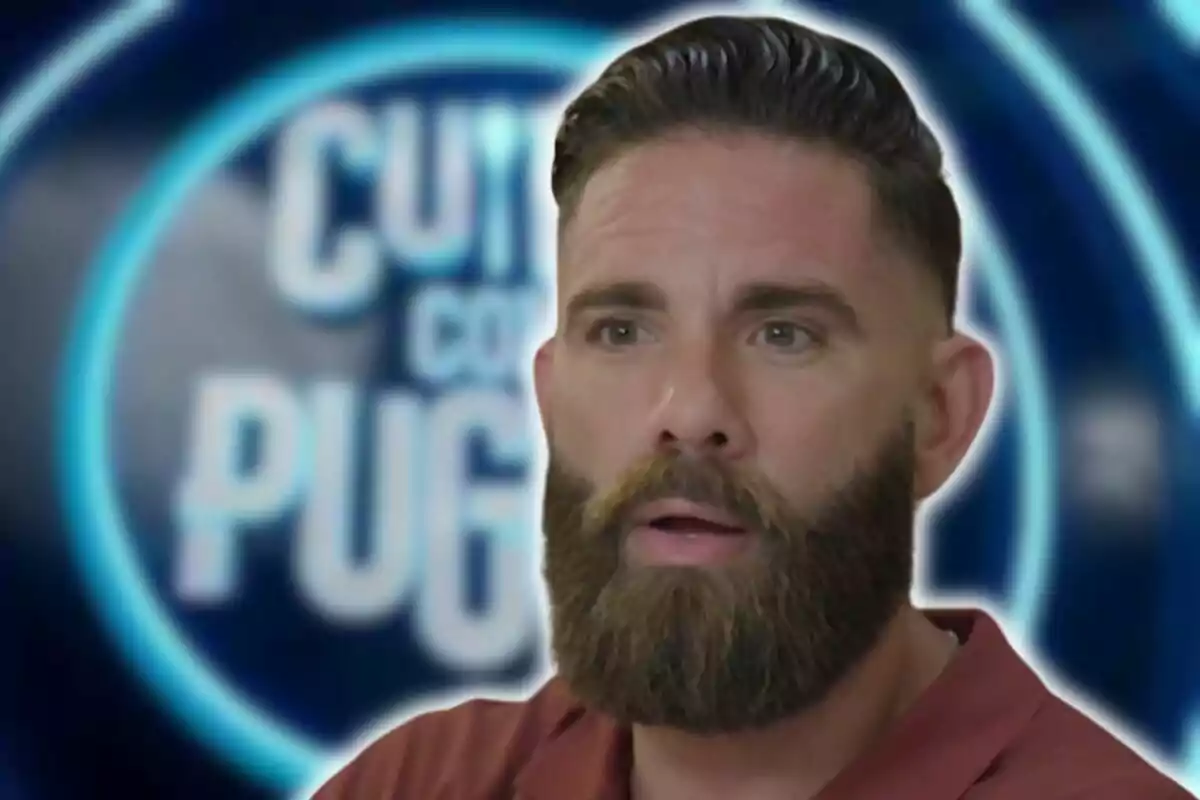 Un hombre con barba y cabello corto aparece en primer plano con una expresión seria, mientras que en el fondo se ve un logotipo borroso con las palabras "CUT" y "PUG".