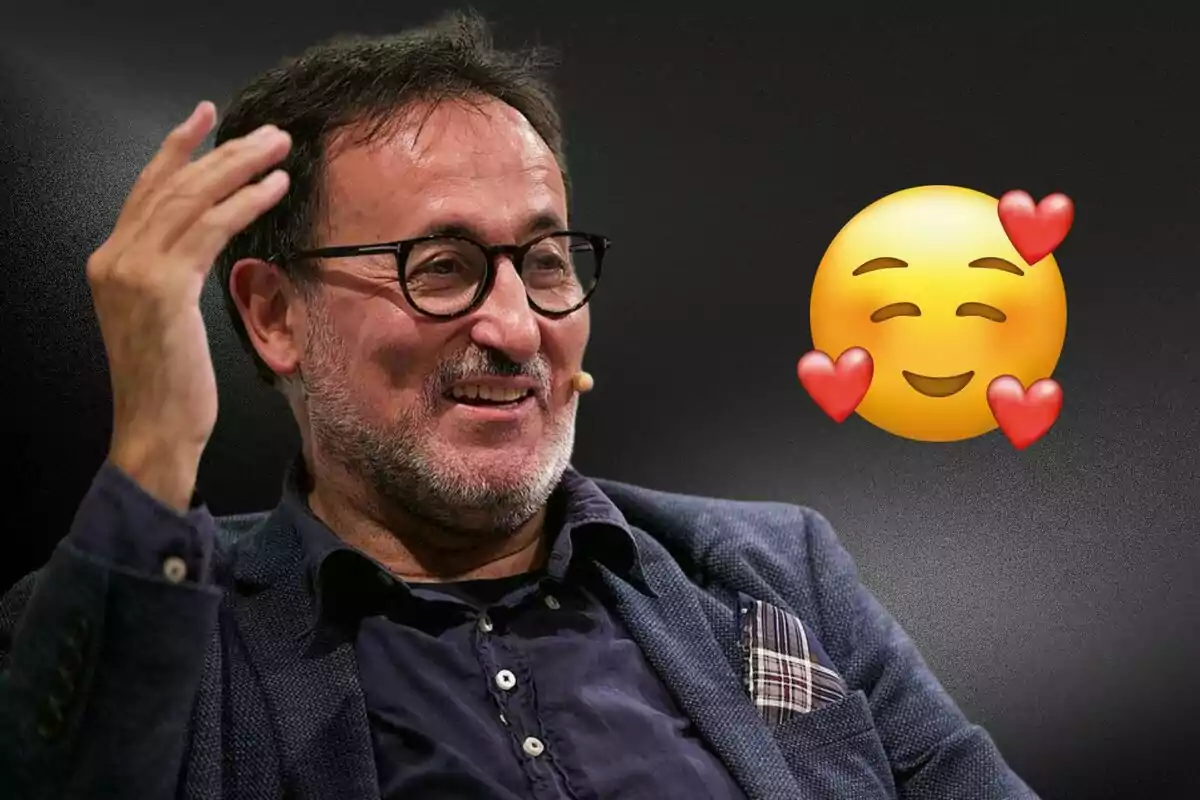 Un hombre con gafas y barba sonríe mientras gesticula con la mano, acompañado de un emoji sonriente con corazones.