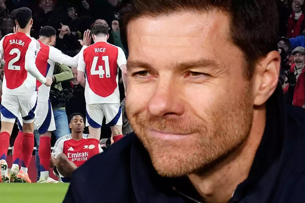 Primer plano de un hombre sonriente con fondo de jugadores de fútbol del Arsenal celebrando en la cancha