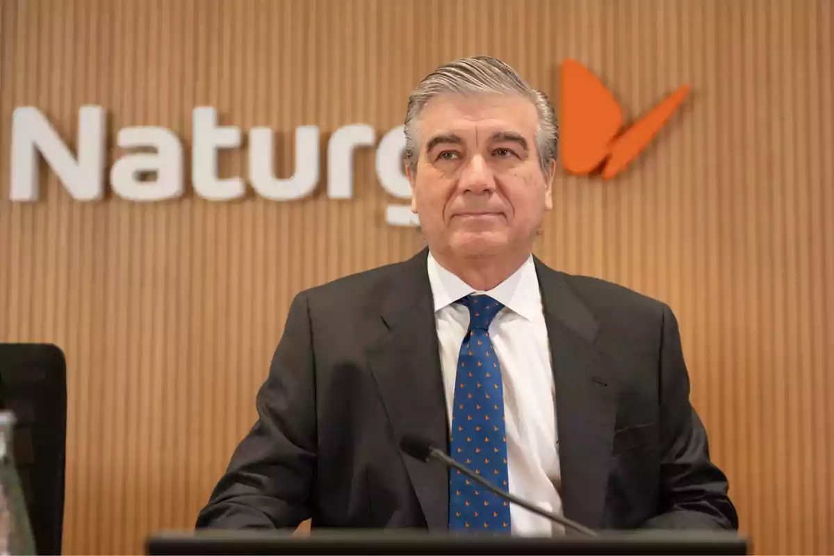 Hombre de traje y corbata azul frente a un fondo con el logo de Naturgy.