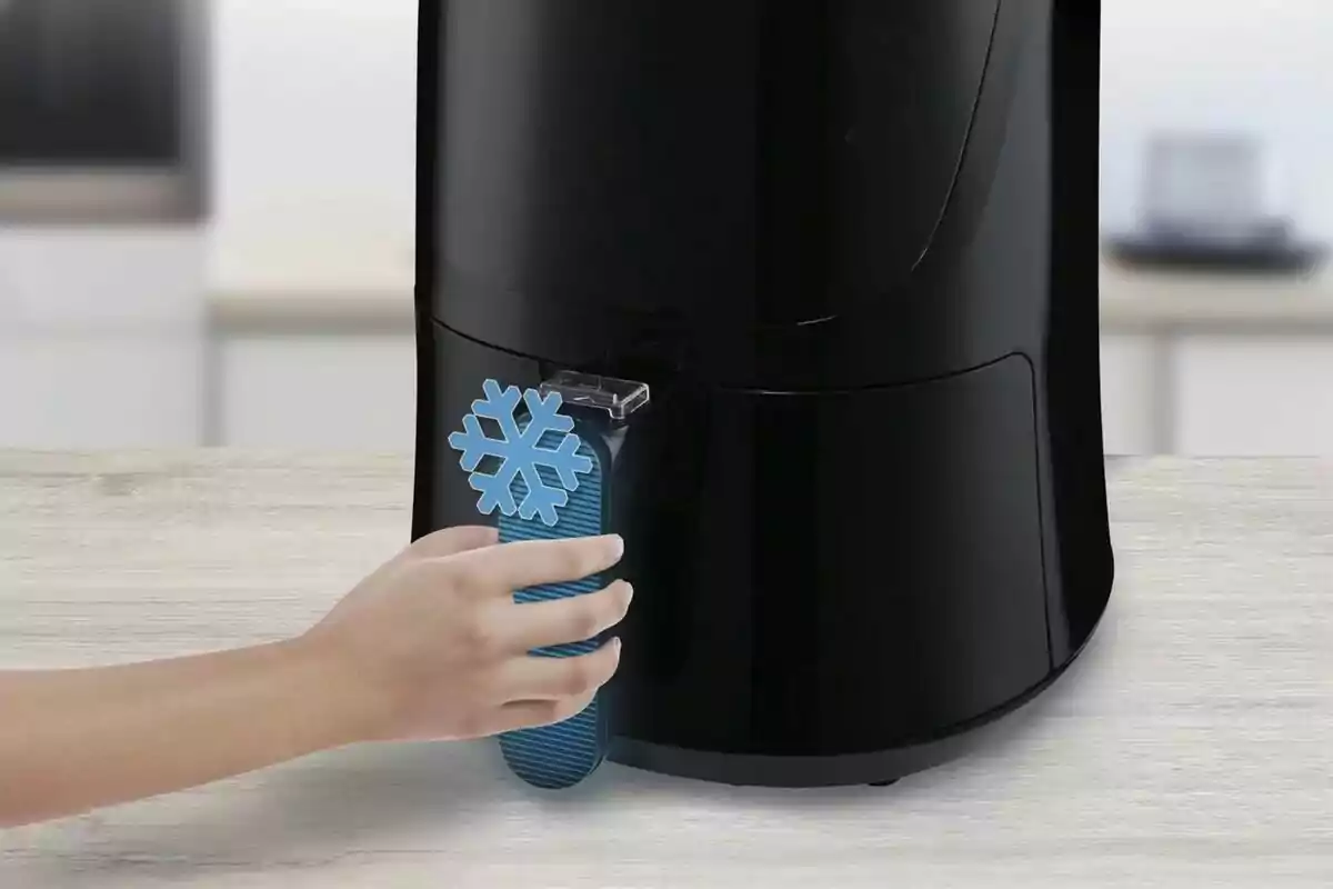 Una mano sosteniendo un objeto azul con forma de copo de nieve frente a un dispensador negro. Una mano sosteniendo un objeto azul con forma de copo de nieve frente a un dispensador negro.