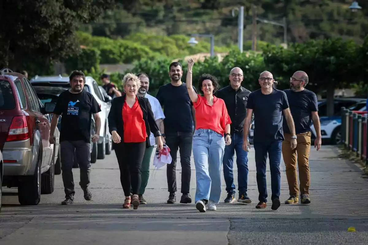 Marta Rovira, Ruben Wagensberg, Oriol Soler, Xavier Vendrell, Jesús Rodríguez y otros fugados caminando por una calle con árboles y coches estacionados a los lados.