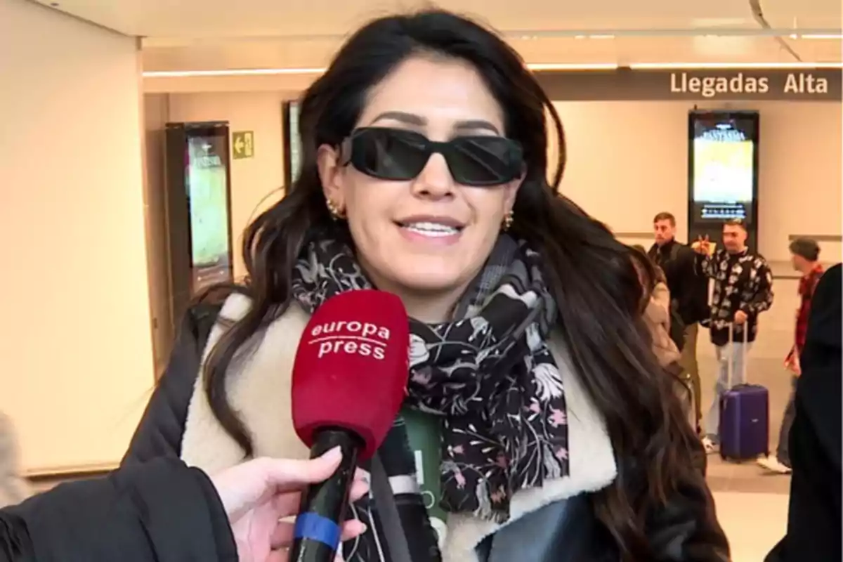 Gabriela Guillén con gafas de sol y bufanda es entrevistada en un aeropuerto, sosteniendo un micrófono de Europa Press. Gabriela Guillén con gafas de sol y bufanda es entrevistada en un aeropuerto, sosteniendo un micrófono de Europa Press.