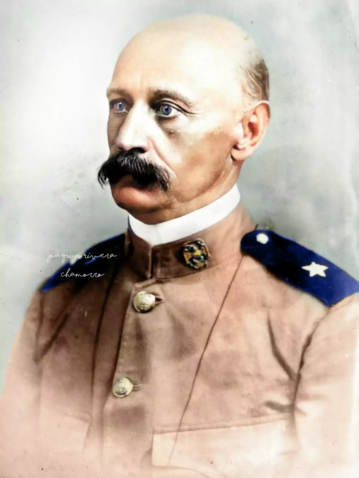 Un hombre con bigote y uniforme militar de color marrón claro con hombreras azules y una estrella blanca. Un hombre con bigote y uniforme militar de color marrón claro con hombreras azules y una estrella blanca.