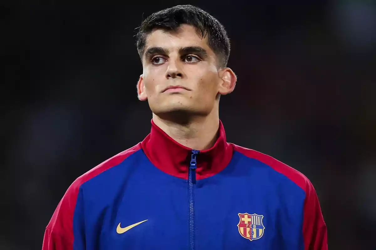 Un jugador de fútbol con chaqueta azul y roja del FC Barcelona en un estadio.