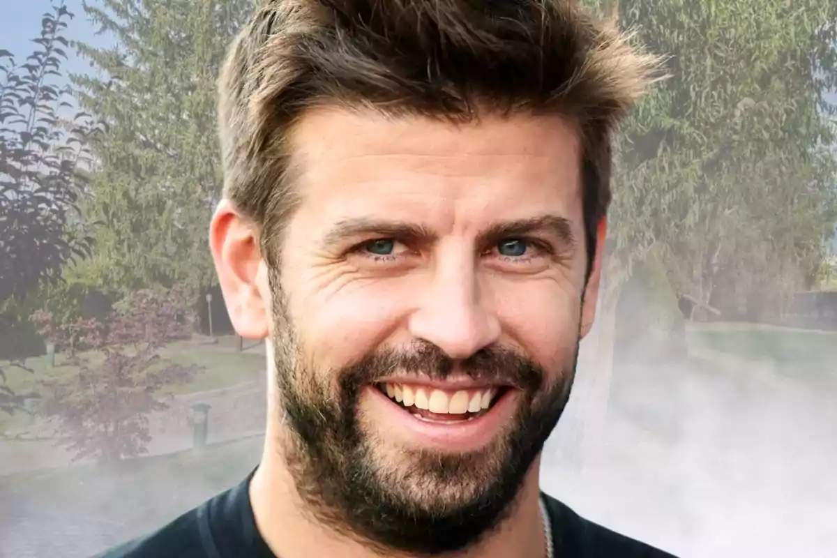 Un hombre sonriente con barba y cabello castaño claro en un entorno al aire libre con árboles de fondo.