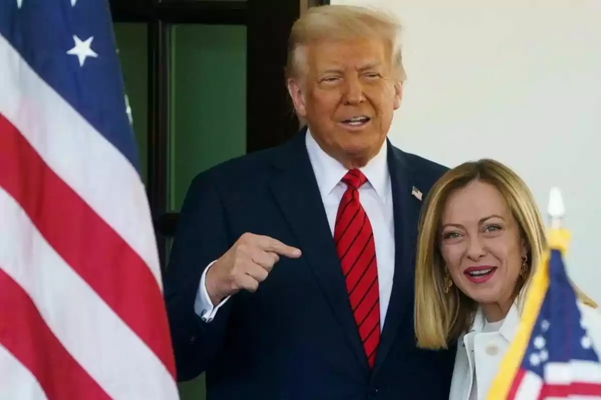 Dos personas posan juntas frente a una bandera estadounidense. Dos personas posan juntas frente a una bandera estadounidense.