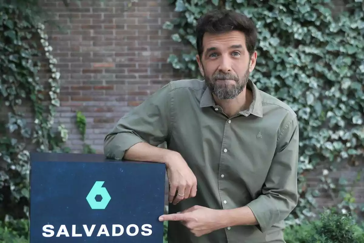 Gonzo con barba y camisa verde señala un cartel que dice "Salvados" con un logotipo de laSexta