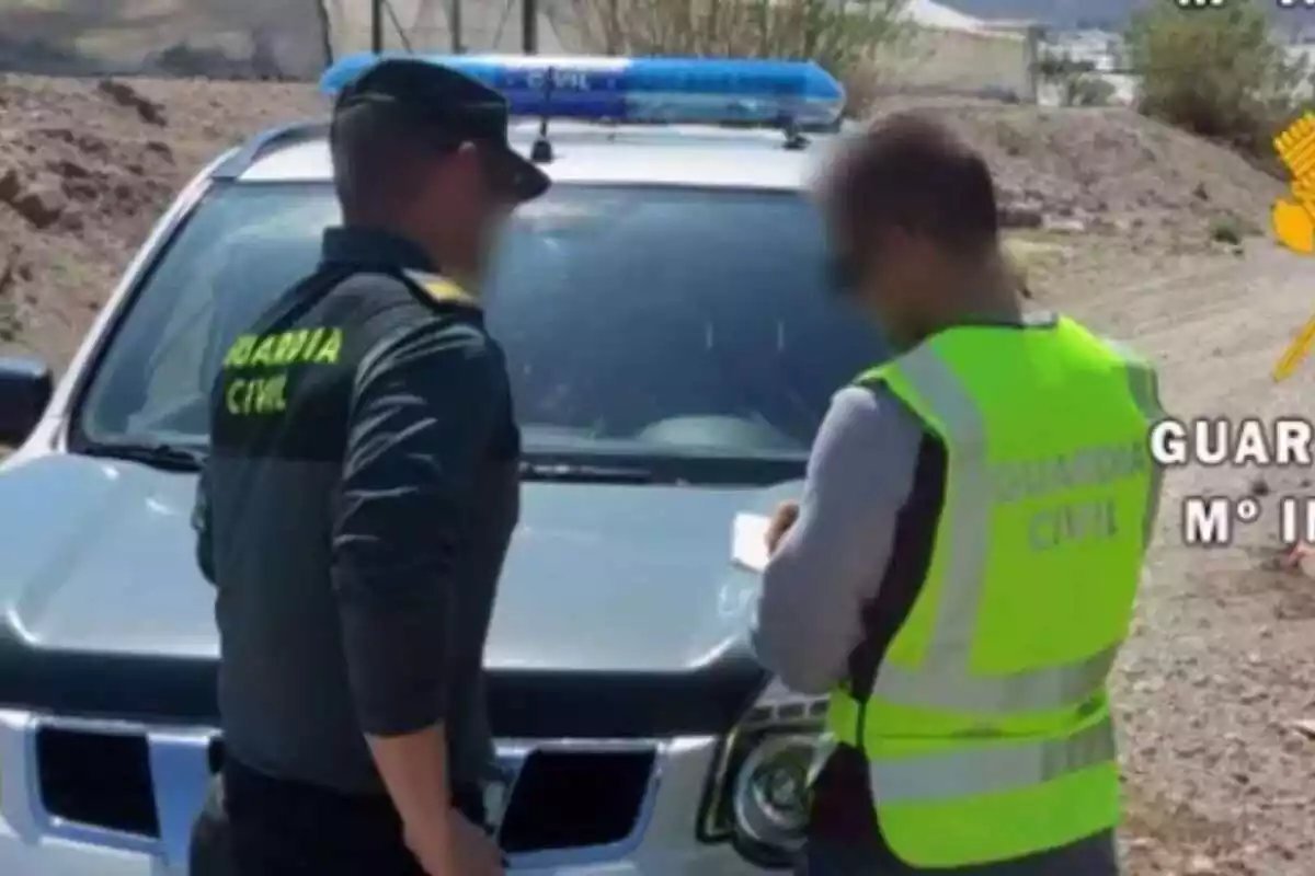 Dos agentes de la Guardia Civil delante del coche y escribiendo