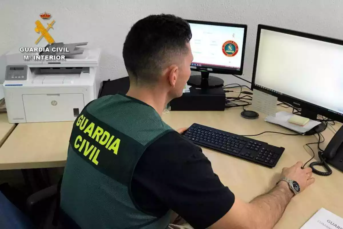 Guardia Civil con un ordenador con dos pantallas y una impresora al lado