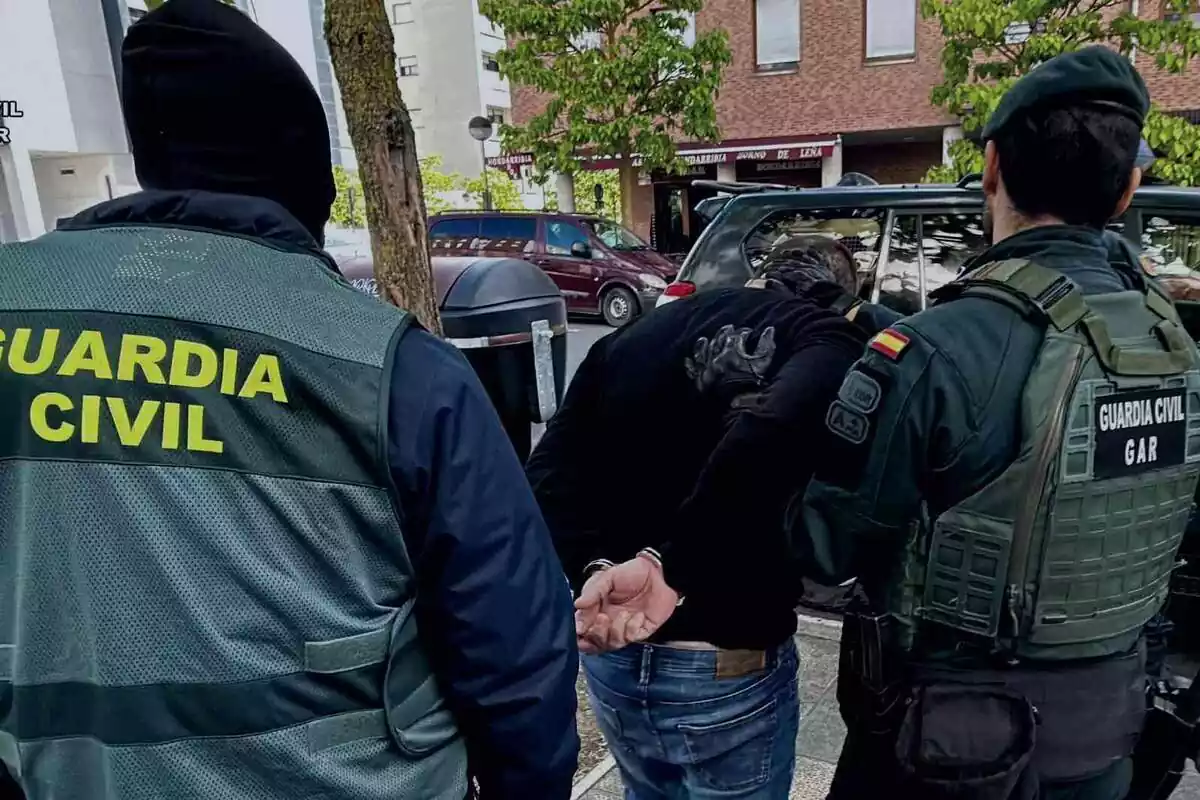 Guardia Civil llevándose detenido a un hombre en la calle