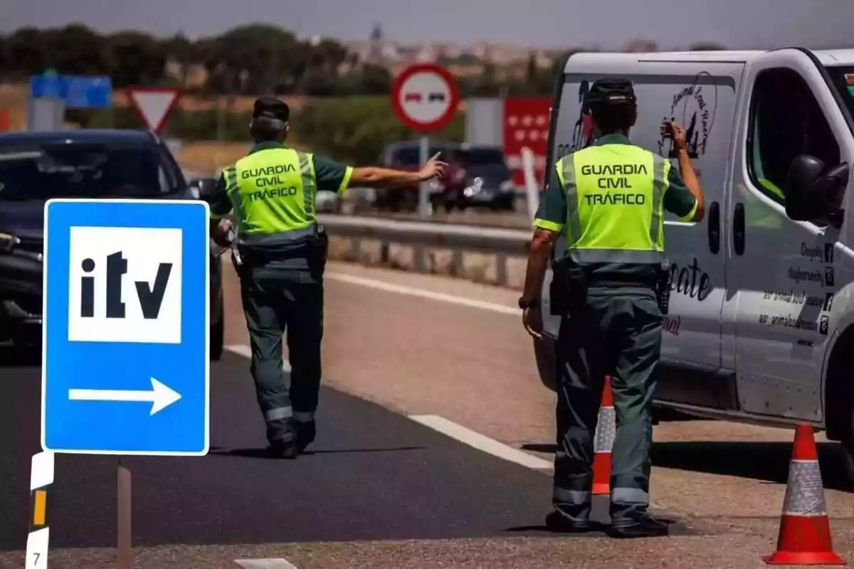Unos agentes de la Guardia Civil detienen a unos vehículos en un control de carretera, con una señal de la ITV