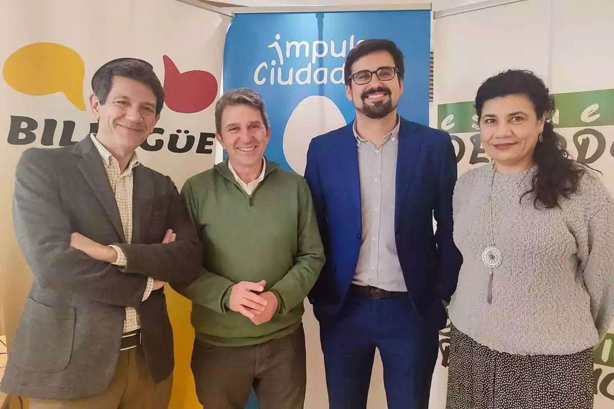 Plano general de Guillermo del Valle posando junto a otras tres personas sonriendo