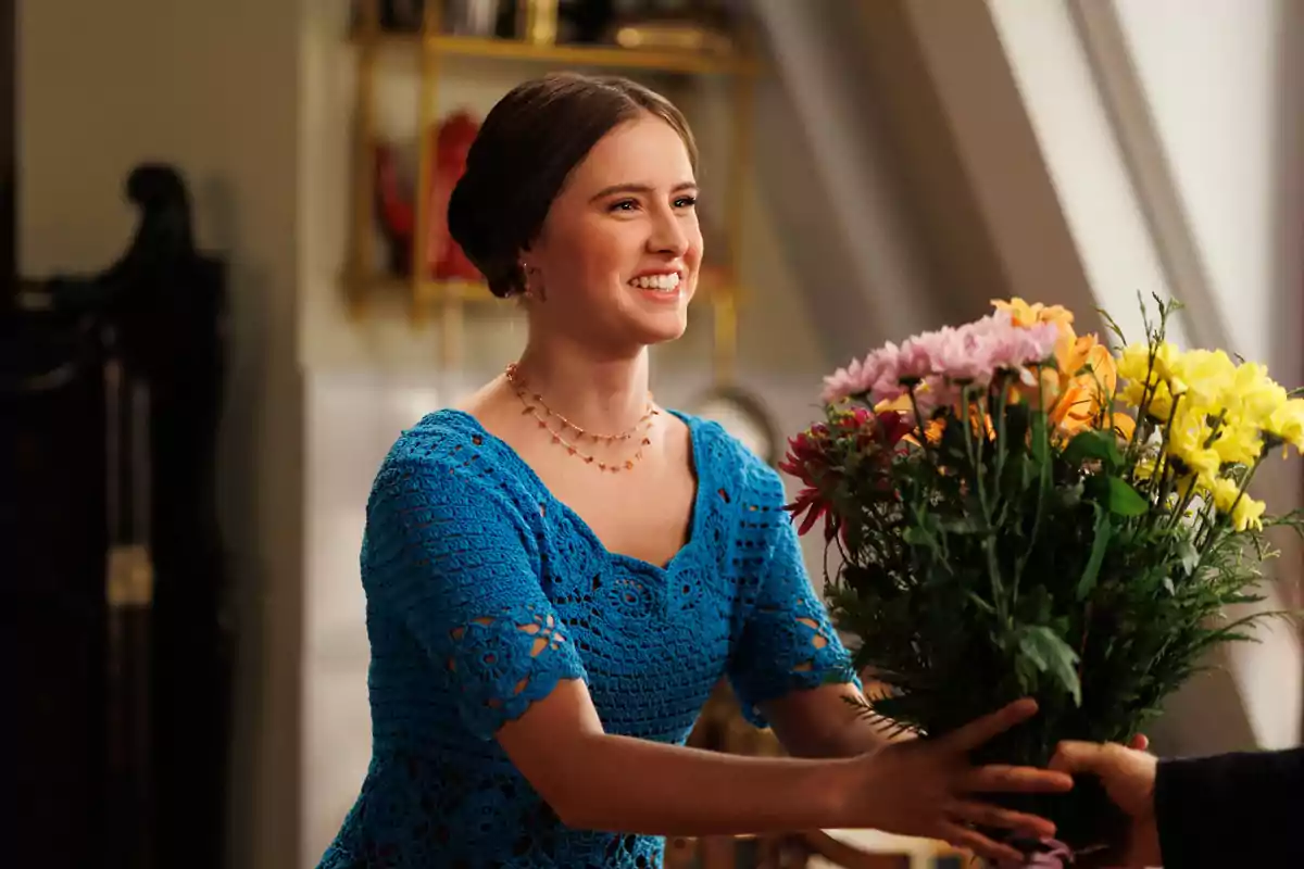 Helena Cortesina sonriente con un vestido azul recibe un ramo de flores de colores en La Moderna.