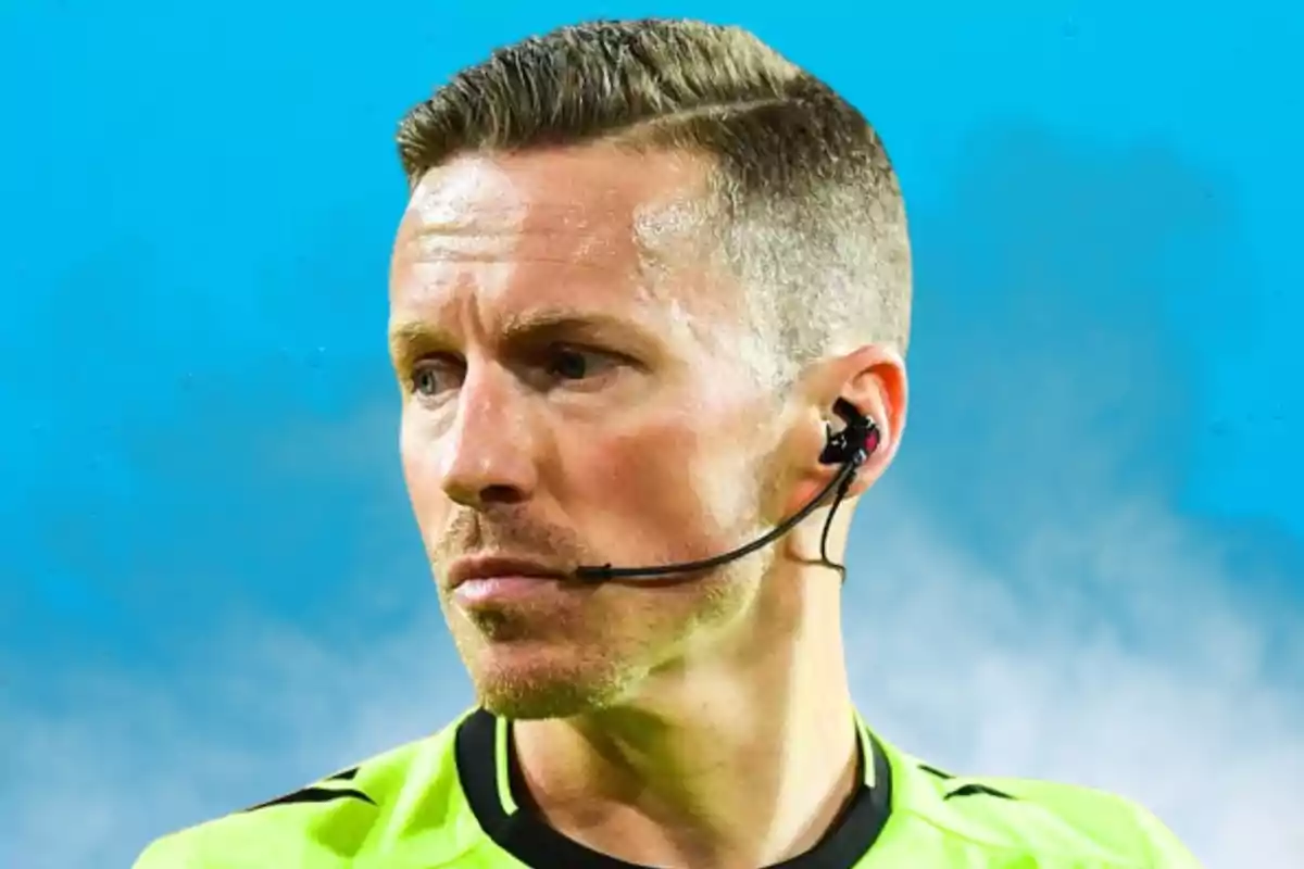 Un árbitro de fútbol con uniforme verde y auricular en un estadio.