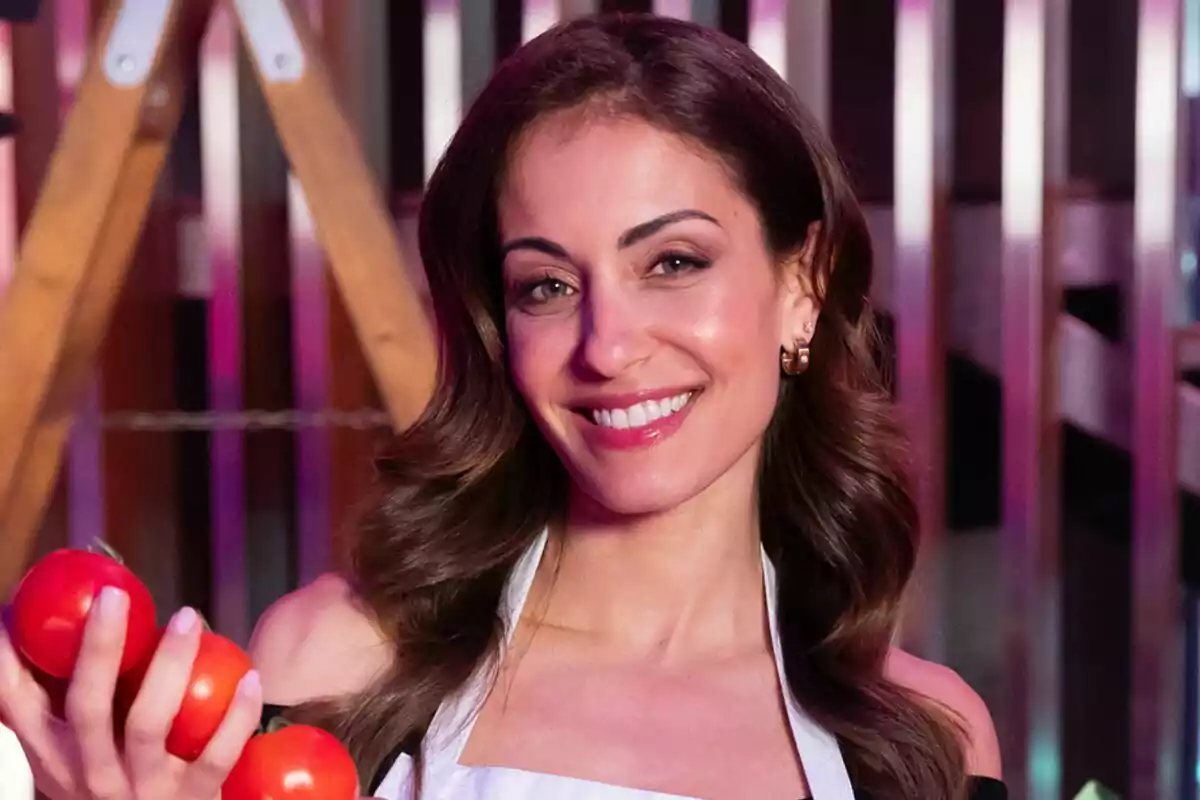 Hiba Abouk sonriendo con delantal blanco y sosteniendo tomates en MasterChef Celebrity.