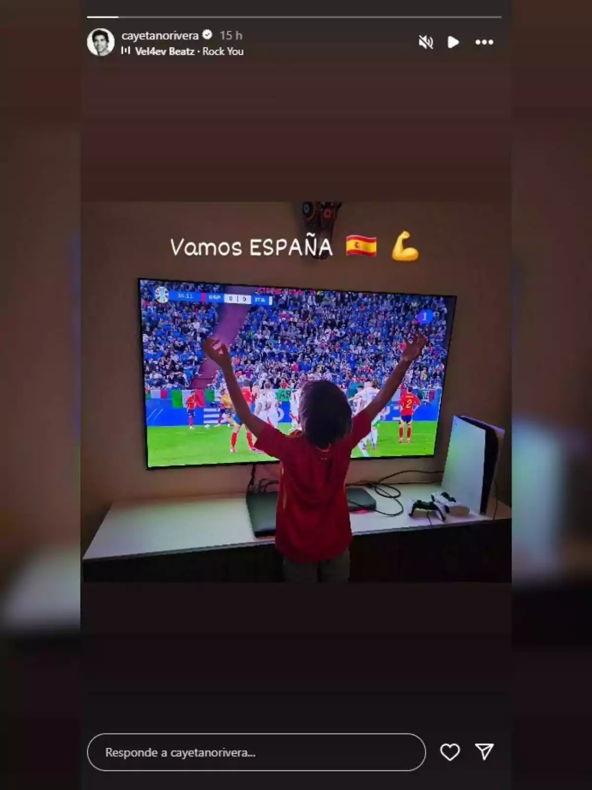 El hijo de Cayetano Rivera con camiseta roja levanta los brazos frente a un televisor que muestra un partido de fútbol, acompañado del texto El hijo de Cayetano Rivera con camiseta roja levanta los brazos frente a un televisor que muestra un partido de fútbol, acompañado del texto