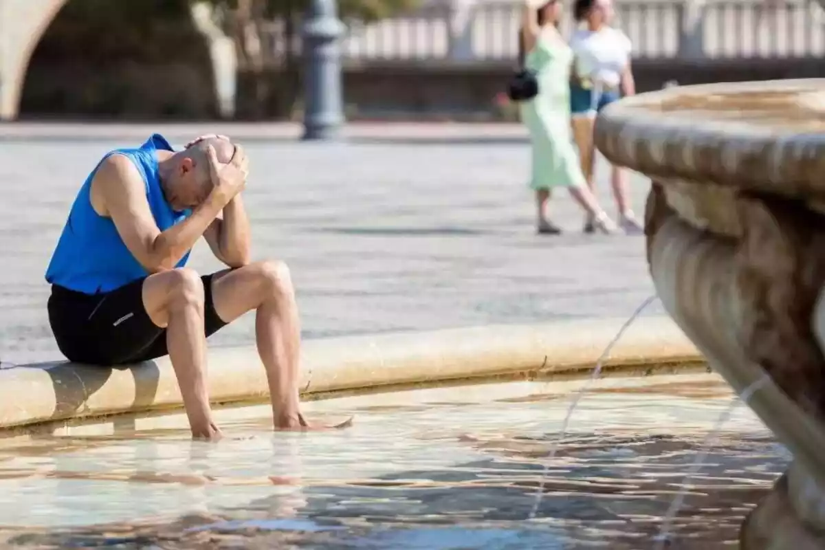 Un hombre refrescándose en una fuente